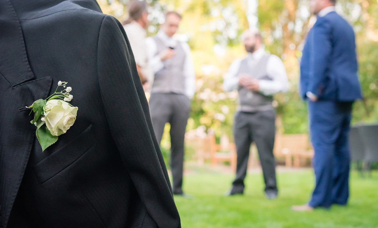 Groom' jacket, with groomsmen stood talking in the background