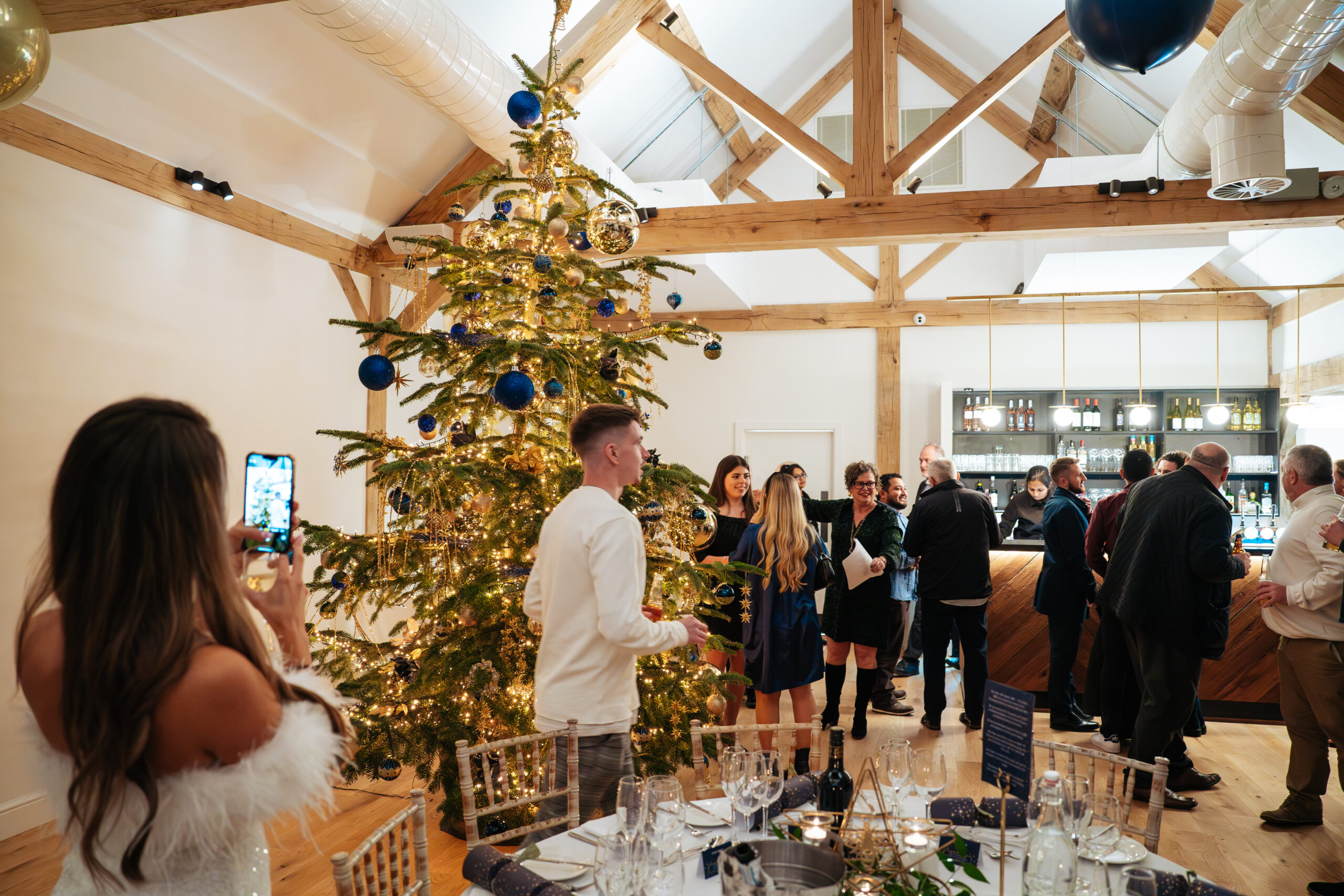 Guests walk next to the decorated Christmas tree inside barn at Alfriston Gardens