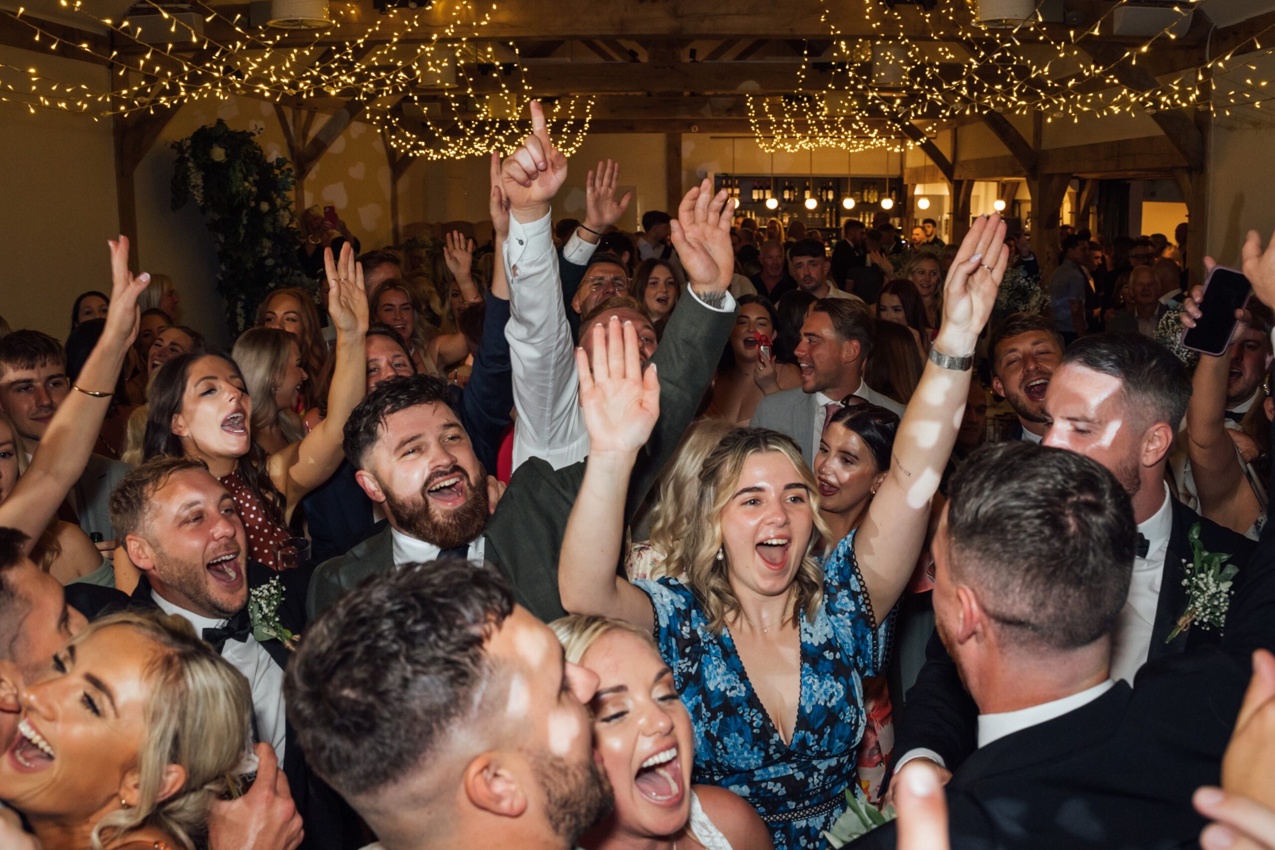 Wedding guests dancing together inside the Woodland Barn at Alfriston Gardens