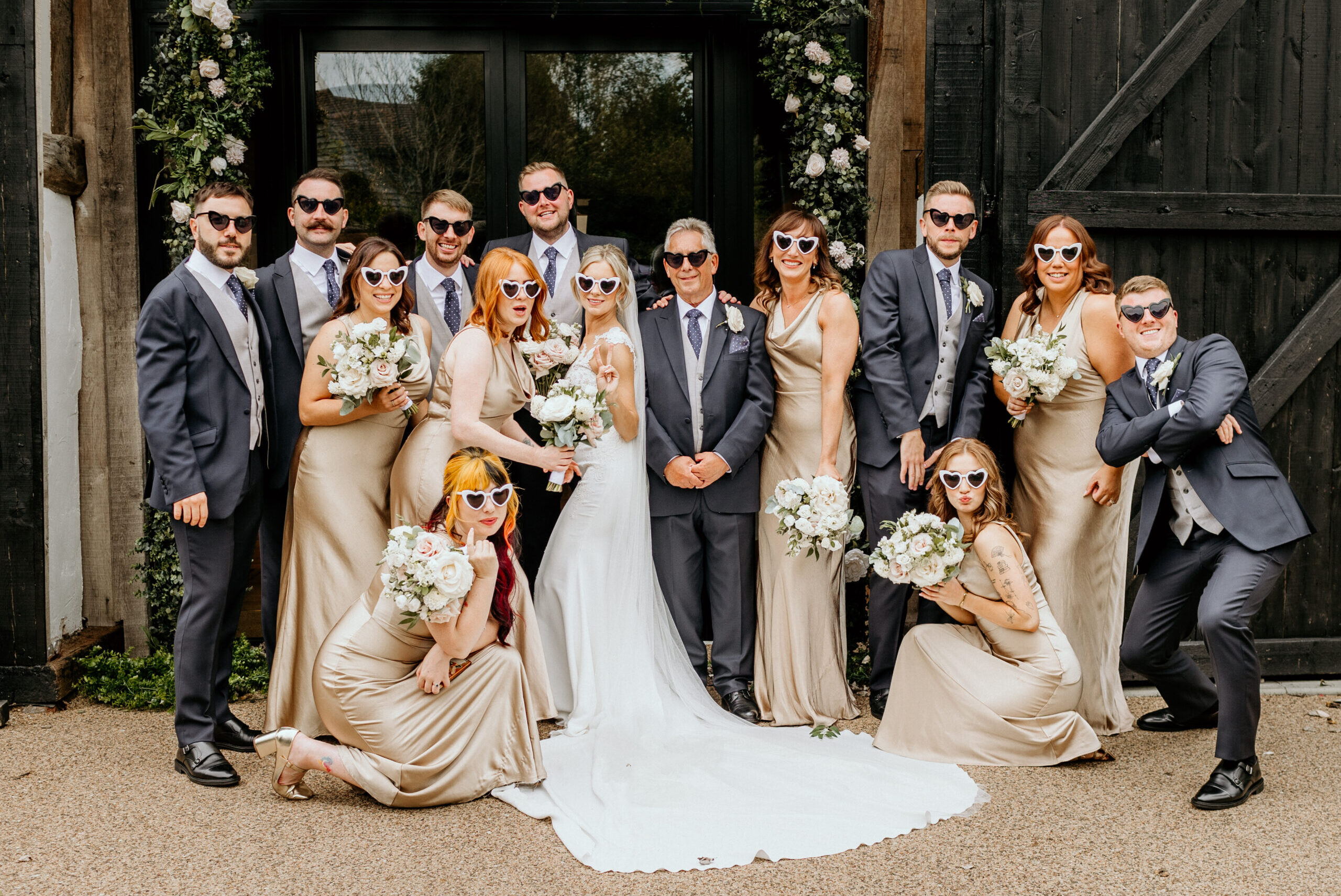 Wedding party pose for photos outside the Century Barn at Alfriston Gardens