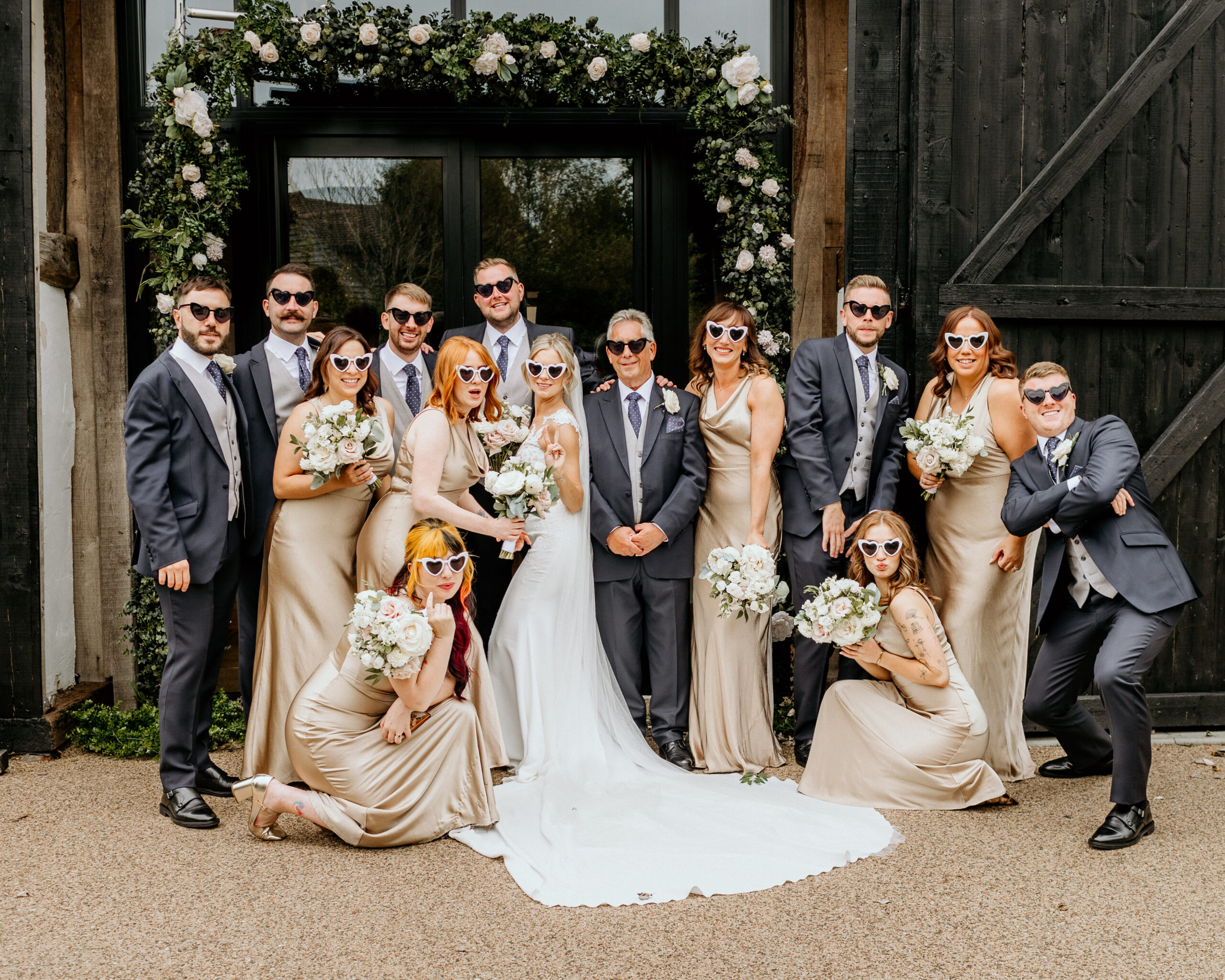 Wedding party pose for photos outside the Century Barn at Alfriston Gardens